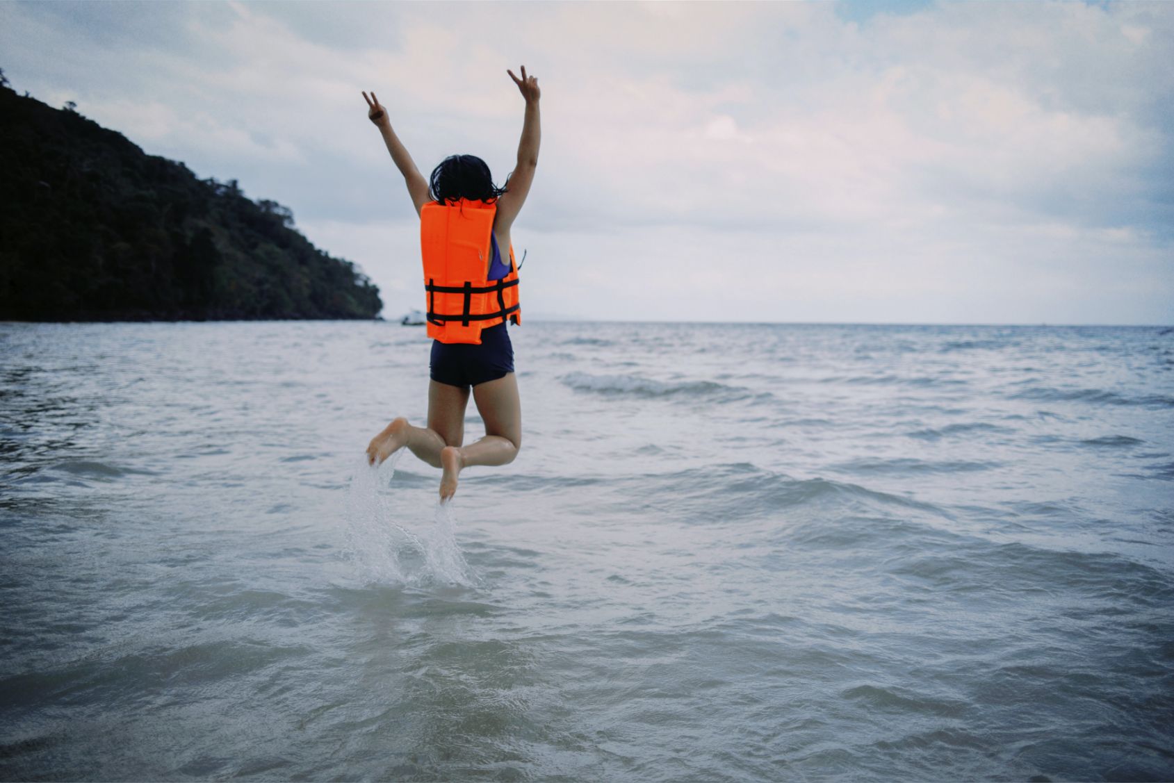Girl in a life jacket jumping into a lake