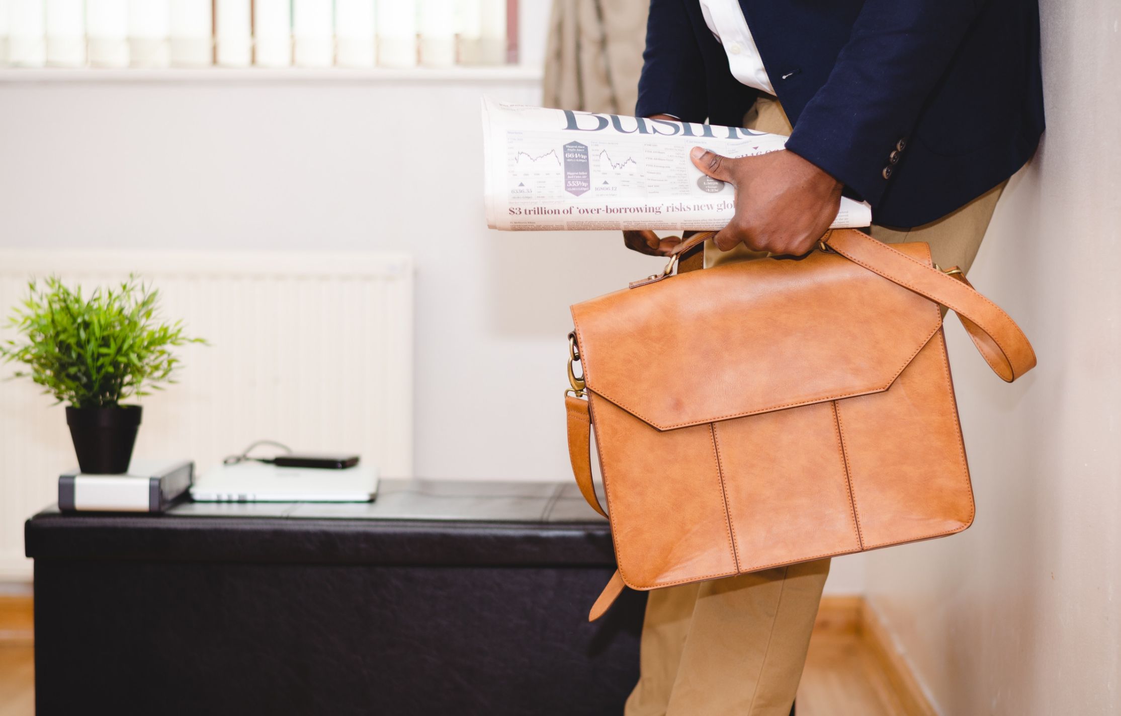 Man holding a business newspaper and a briefcase