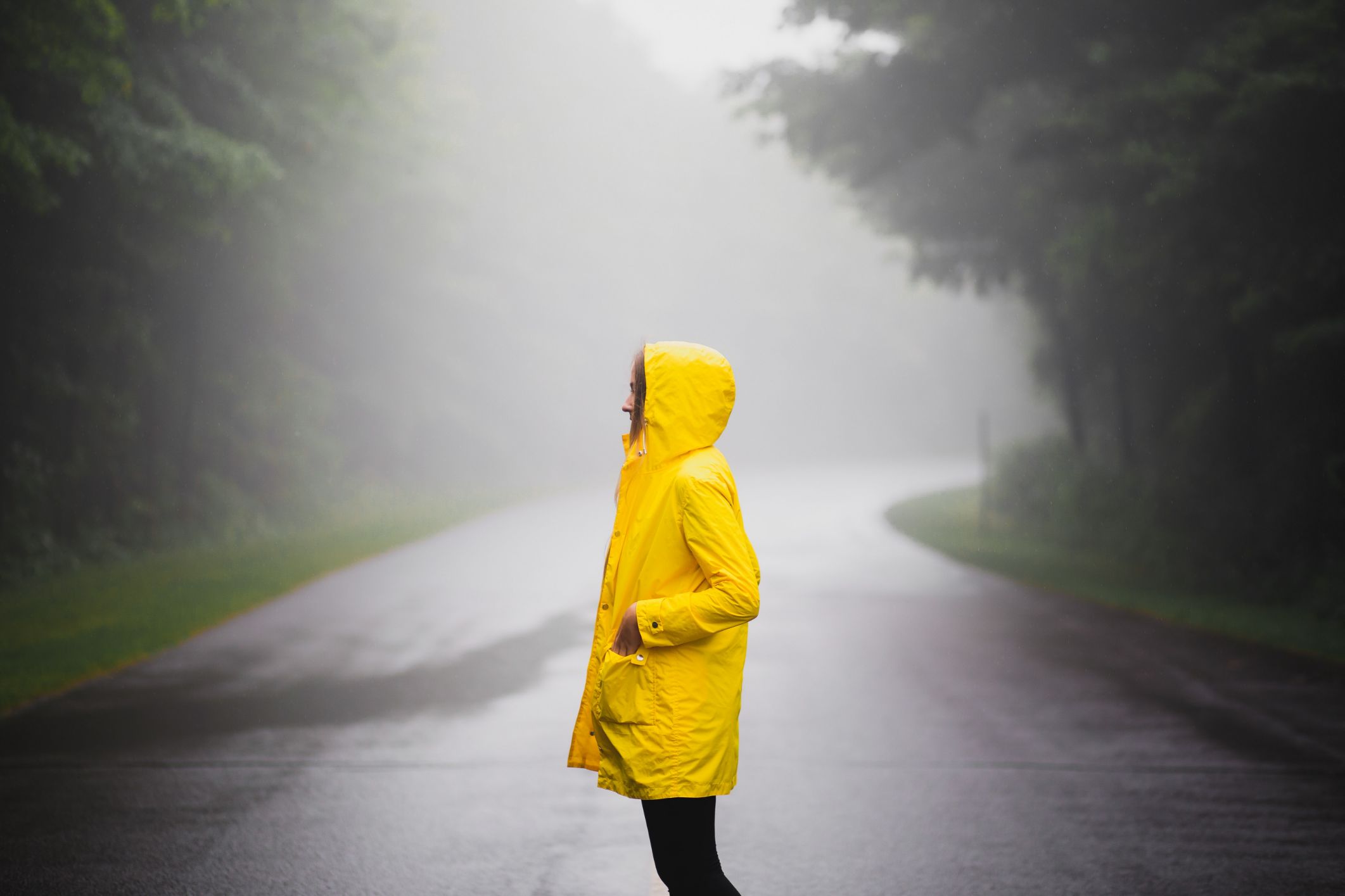 woman standing on a road in a raincoat